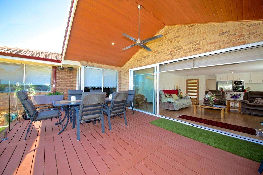 A charming covered patio with an outdoor dining set and ceiling fan seamlessly connects to the spacious living room through sliding glass doors, perfect for enjoying Connolly's serene elegance.